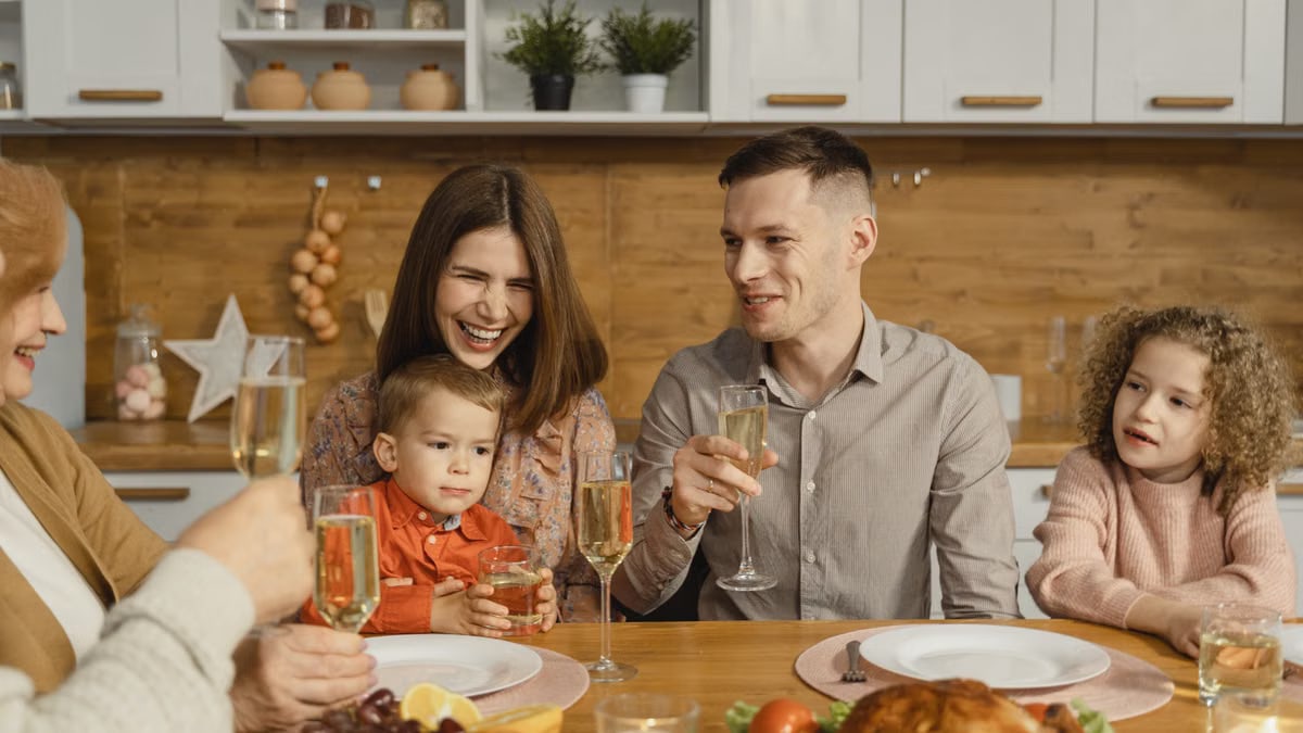 A joyful family celebrating together with food and champagne at a cozy dinner table.