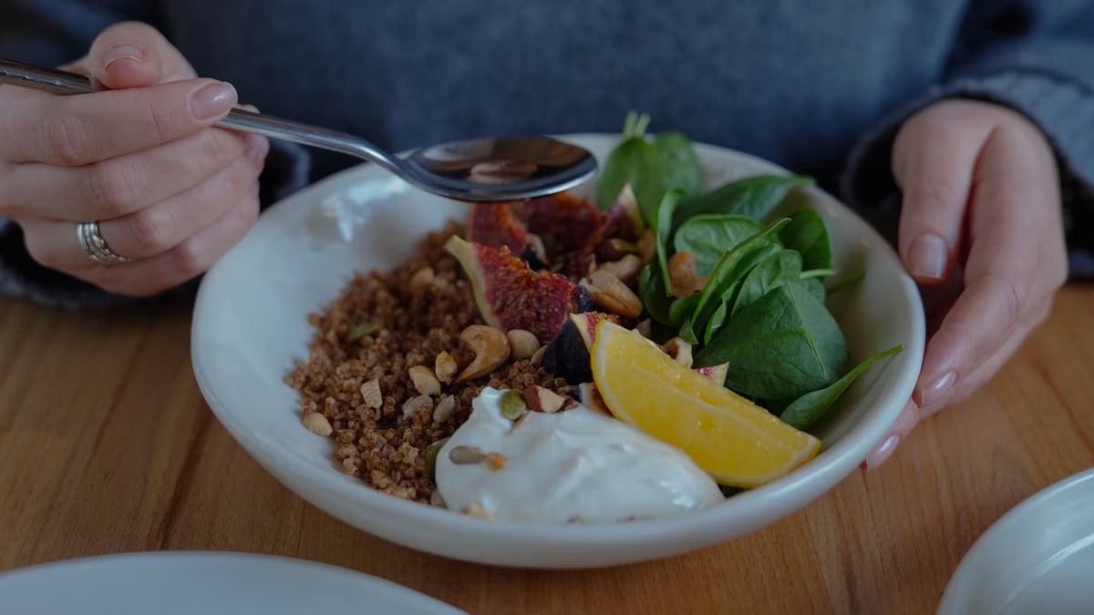 A vibrant brunch bowl with fruit, greens, and nuts for a nutritious meal.